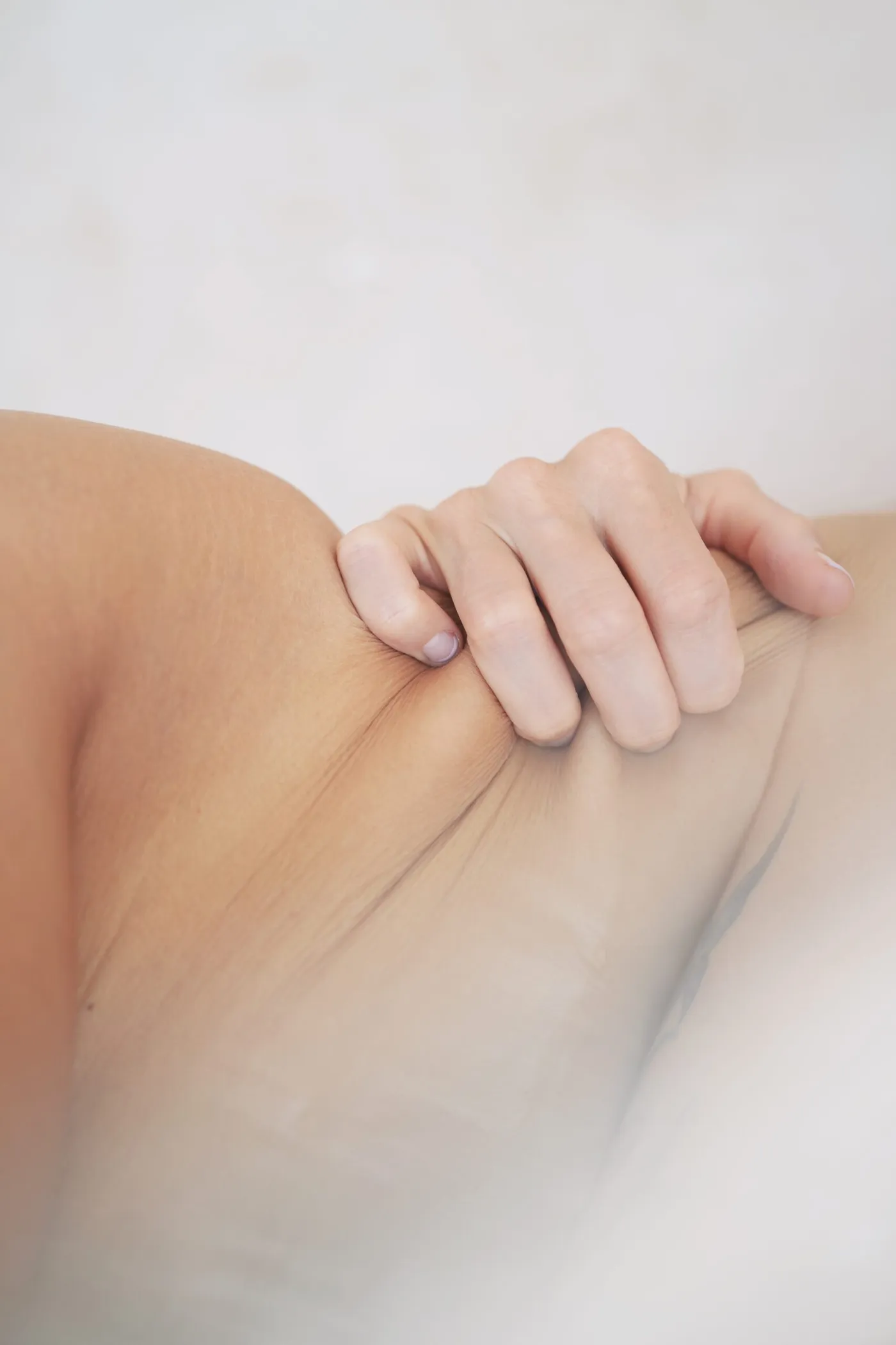 A hand resting on bare skin, close up, in soft daylight